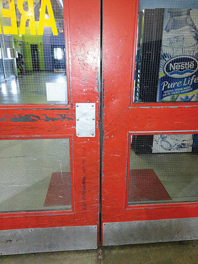     Is this the best we can do? The missing paint from these doors reveals how people smash them open with their hockey bags. Note that the bottom left lite has already been broken and replaced by scratched-up plastic.   