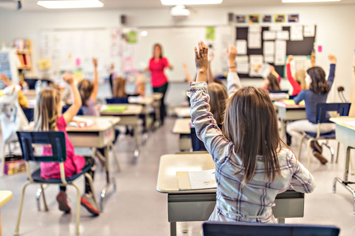 Woman in classroom with hand raised